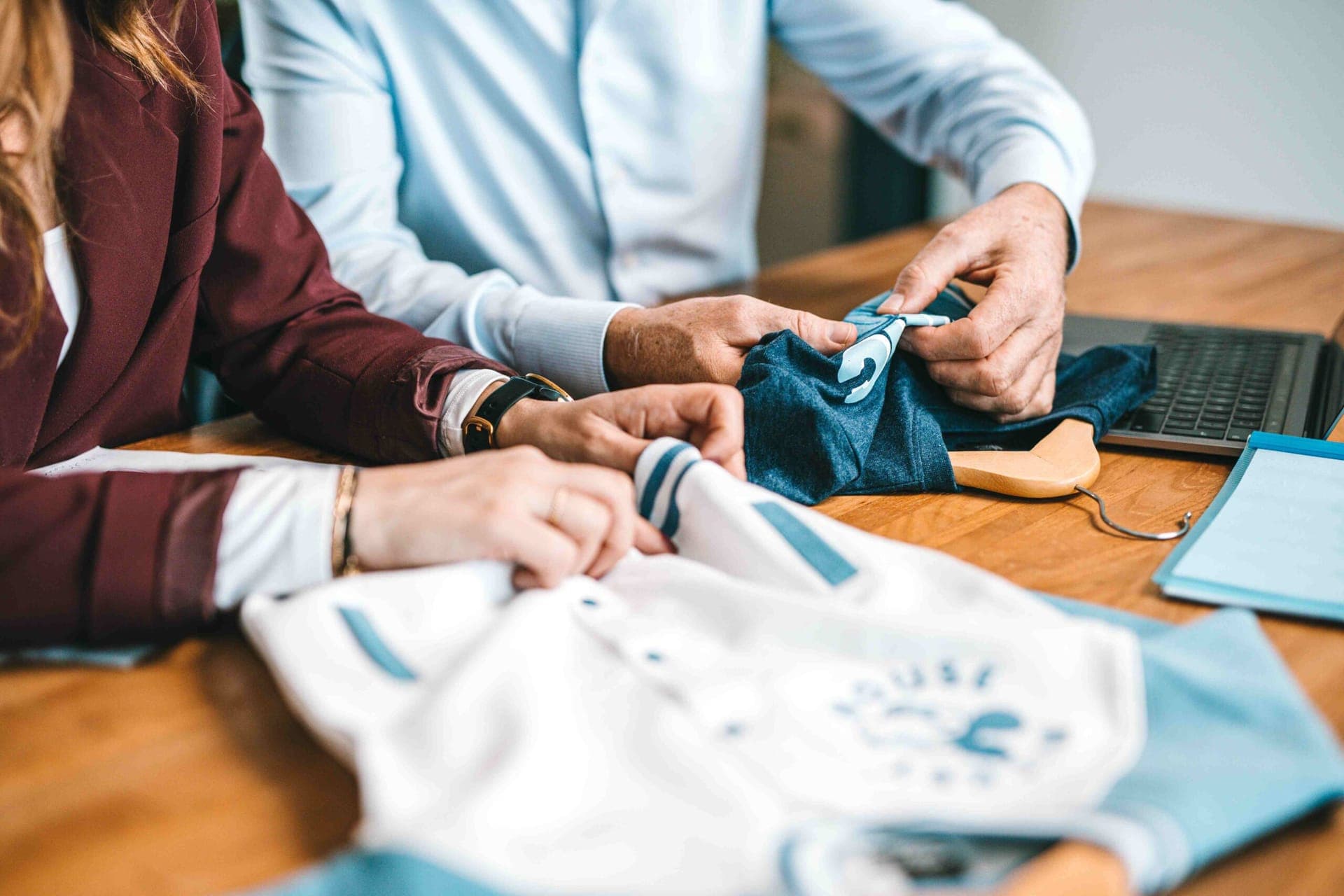 Collega's bekijken kledingstalen: een wit varsity-jack en een blauw t-shirt