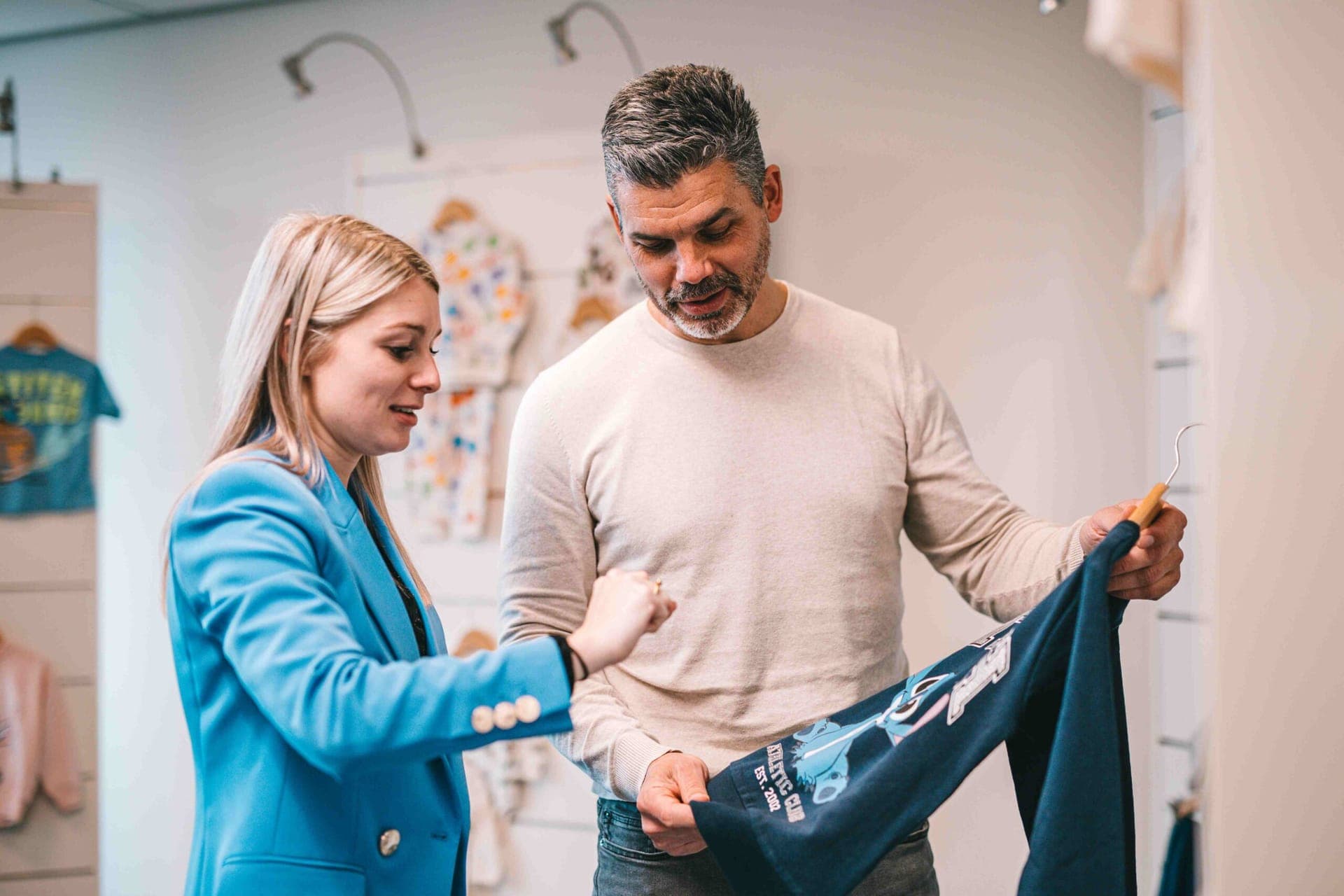 Twee collega's bekijken een donkerblauwe Stitch-sweater in de showroom