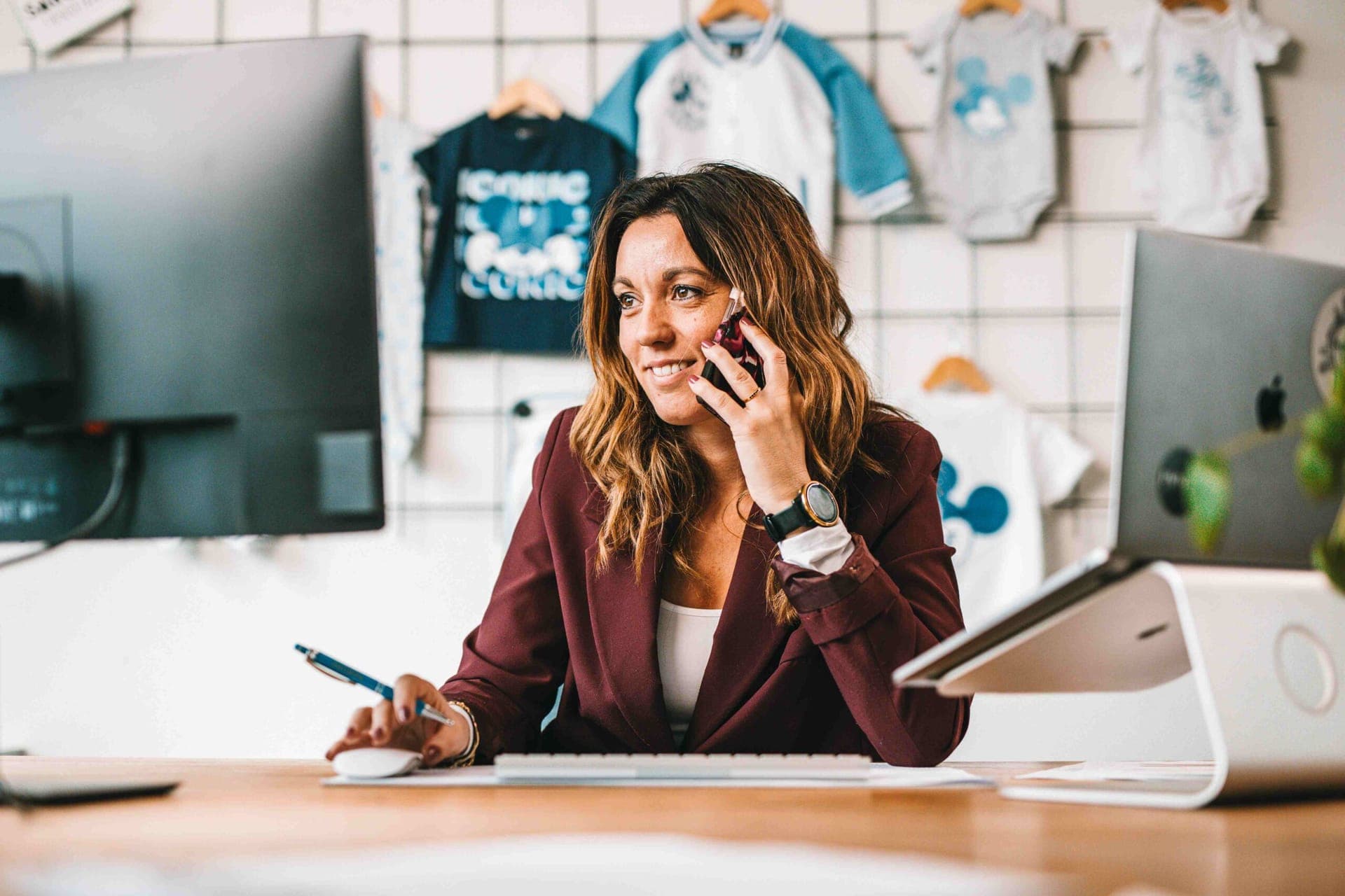 Collega aan de telefoon achter haar bureau, met gelicentieerde Mickey Mouse-kinderkleding aan de muur erachter
